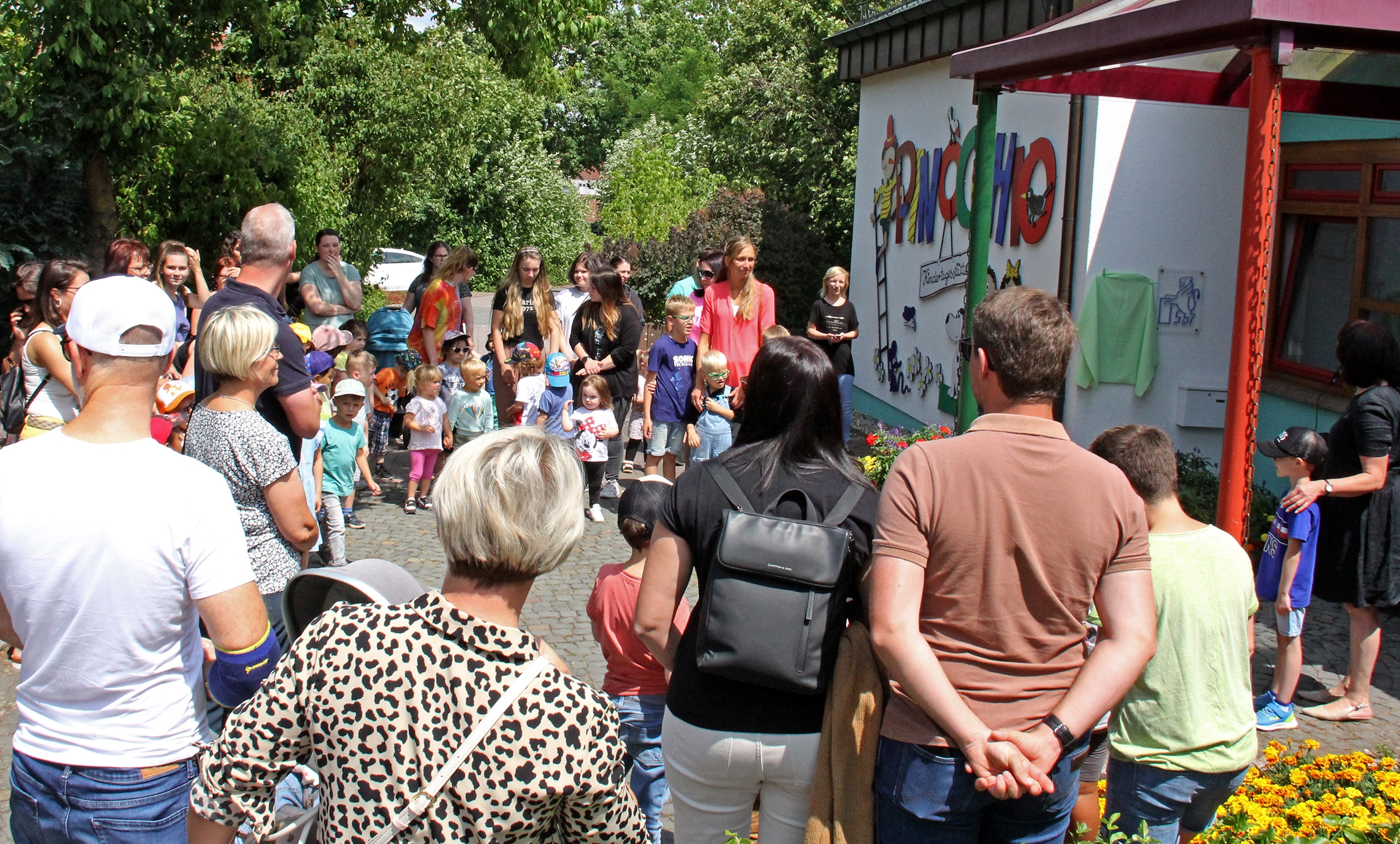 Kinder, Eltern und Erzieherinnen vor der Enthüllung am Haupteingang