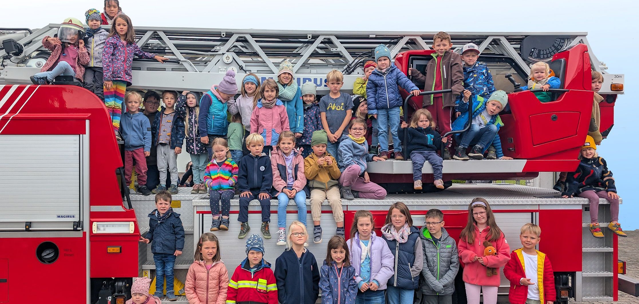 Kinder auf dem Feuerwehrauto beim Tür-Öffner-Tag