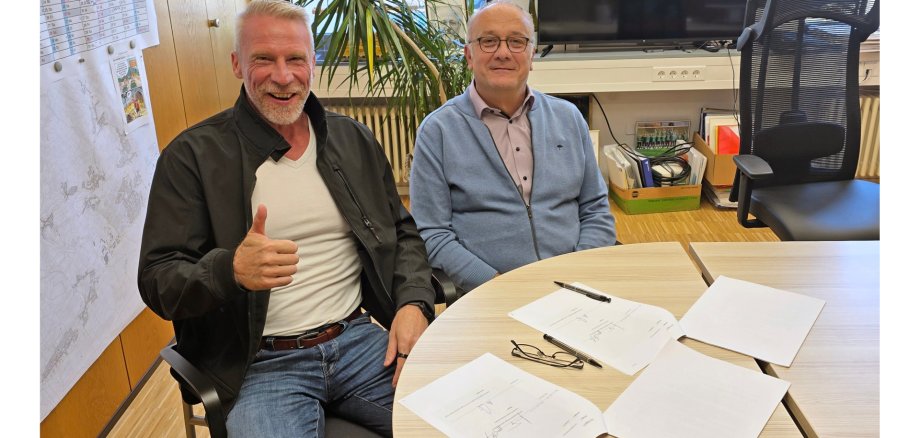 Zimmer und leydecker am Tisch vor den unterzeichneten Verträgen